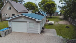 Ein kleines, eingeschossiges Gebäude mit Garage, überdachter Terrasse und Kiesweg.