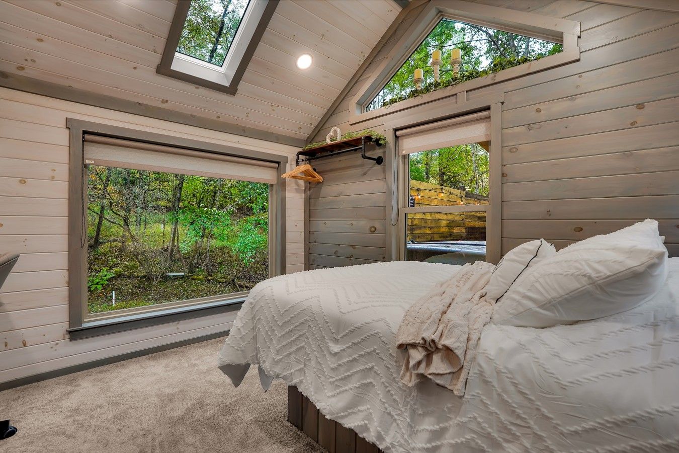 Une chambre à coucher avec un grand lit, deux fenêtres et une lucarne.