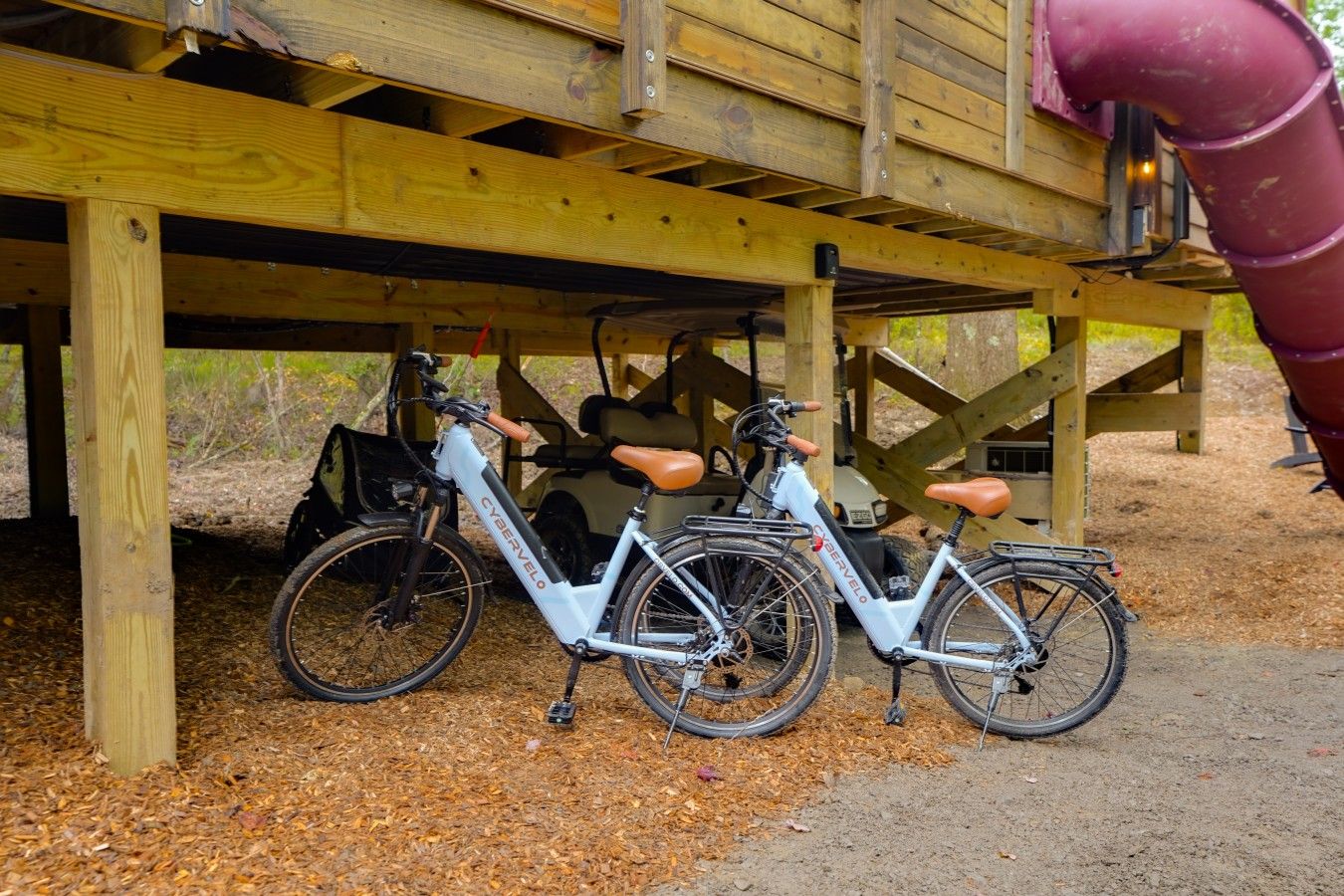 Two bicycles parked under a wooden structure with a slide.