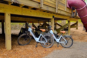 Two bicycles parked under a wooden structure with a slide.