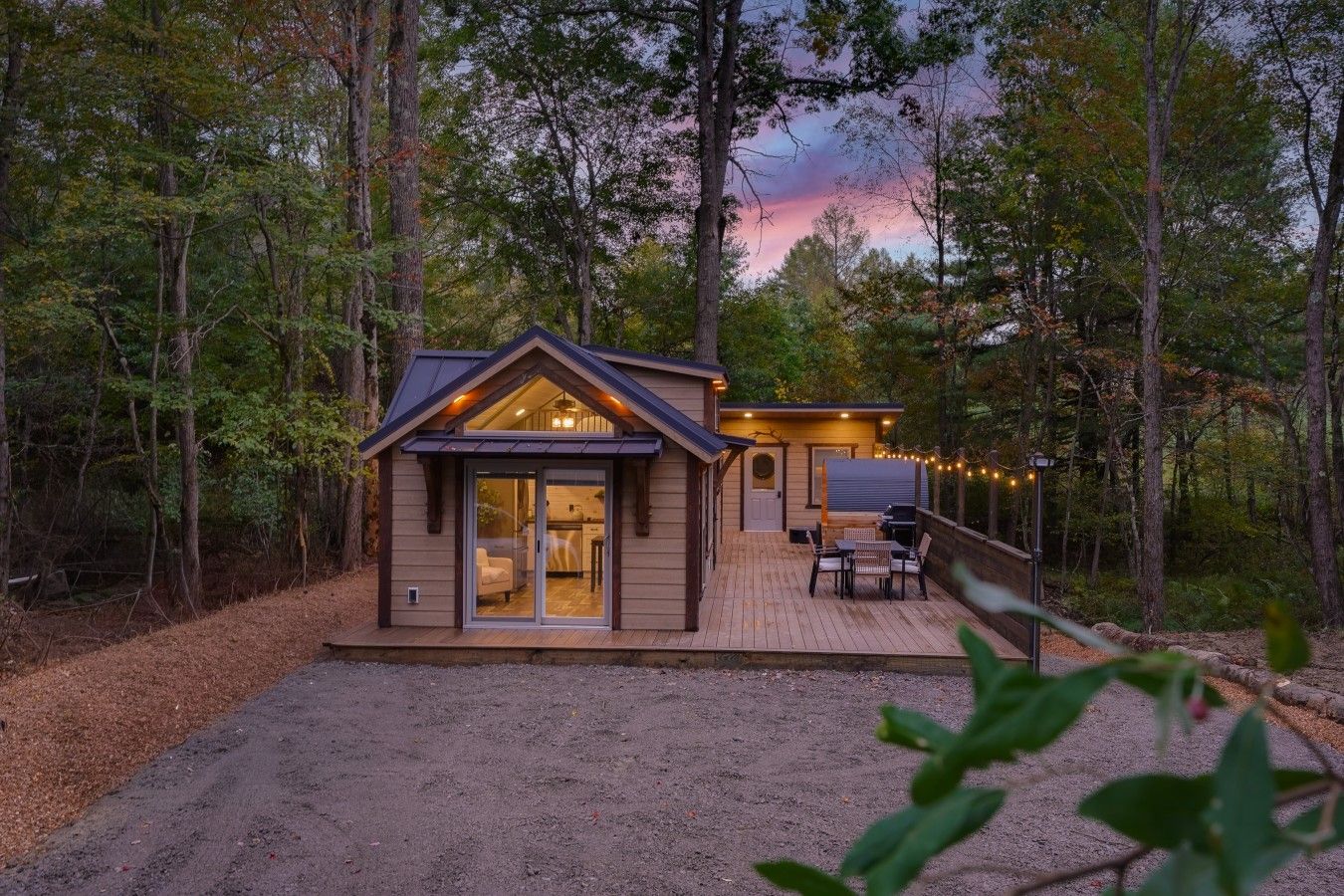 Une cabane dotée d’une terrasse, d’une porte-fenêtre coulissante et d’un petit espace extérieur aménagé pour s’asseoir.