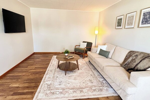 A living room with a sofa, a coffee table, a lamp, and a rug.
