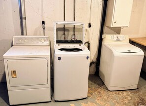 A laundry room with three white appliances, including a dryer and two washing machines. - Serenity on Arthur Beatrice (Beatrice)