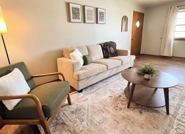 Una sala de estar con sofá, sillón y una mesa redonda de centro.
