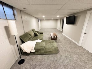 Ein Zimmer mit einem grünen Sofa, einem kleinen Tisch und einer Lampe.