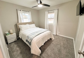 A bedroom with a bed, nightstand, and a ceiling fan.