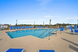 Une piscine avec des chaises bleues et un panneau indiquant la présence d’un sauveteur.