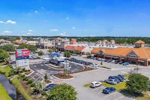 Une zone commerciale avec un panneau indiquant la présence de magasins Tanger Outlets, des parkings et un ensemble de boutiques.
