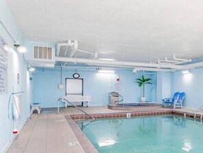 An indoor swimming pool with a tiled floor, a bench, a small table, and a plant. - Phoenix East II 2092 (Orange Beach)