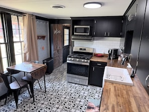 Une cuisine de taille réduite, équipée d’une cuisinière, d’un four à micro-ondes et d’un évier.