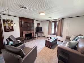 Ein Wohnzimmer mit Kamin, Ledersofas, einem Couchtisch und einem Fernseher.
