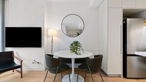 Cozy dining corner featuring a round white table, comfortable seating, and a mounted flat-screen television.    - Melbourne Skyline High-Rise Suite | City Views & Pool Access (Melbourne)