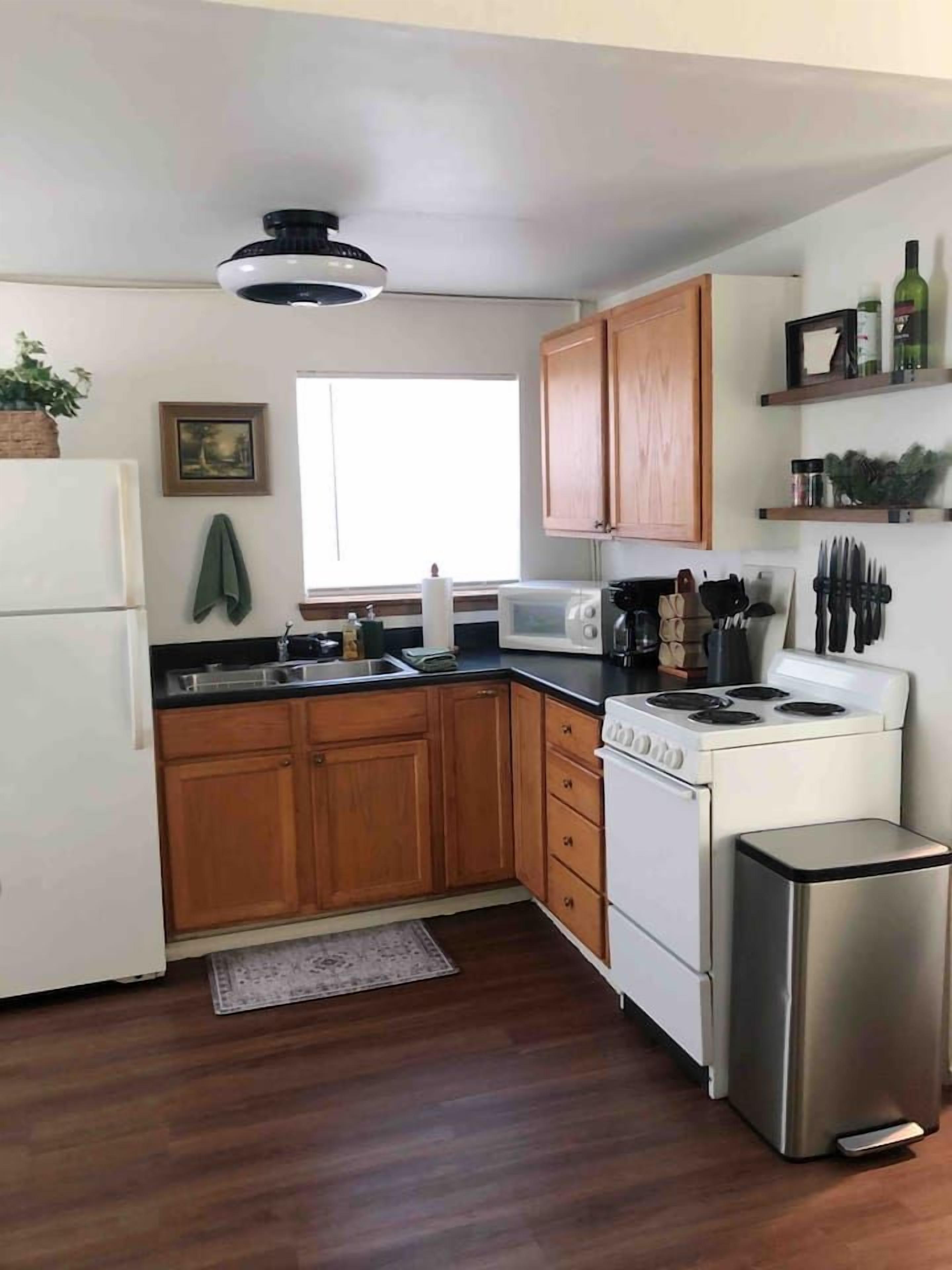 A kitchen with wooden cabinets, a microwave, a stove, and a refrigerator.