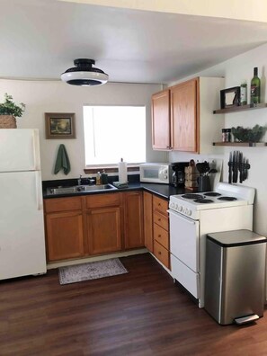 A kitchen with wooden cabinets, a microwave, a stove, and a refrigerator.