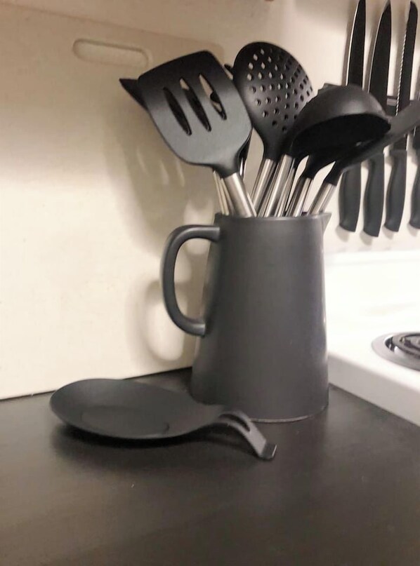 A kitchen utensil holder with various utensils, including spatulas and a ladle, on a countertop.