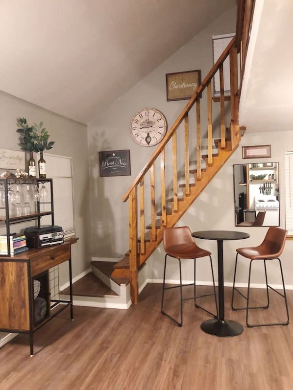 A staircase with wooden railings, a wall clock, and a wine rack with bottles.