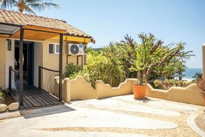 A building with a tiled roof, an air conditioning unit, a covered entrance, and a view of the ocean. - Oceanview Hotel w/ Balcony, Steps to Zicatela (Puerto Escondido)