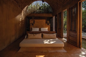 A bedroom with a large bed, wooden walls, and a view of greenery outside. - Oaxaca Villa: Private Pool, Beach Access & Garden (Puerto Escondido)