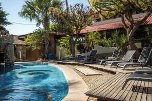 A swimming pool with lounge chairs and a stone wall. - Zicatela Oceanview Oasis: Pool, Hot Tub, Surf (Puerto Escondido)