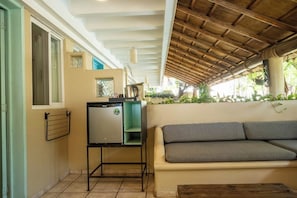 A compact living space with a kitchenette, a sofa, and a wooden table. - Zicatela Oceanview Oasis: Pool, Hot Tub, Surf (Puerto Escondido)