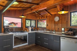 Una cocina con paredes de madera, estufa a gas, microondas y un lavamanos.
