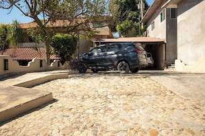 A stone-paved driveway leading to a car parked in a garage. - Oceanview Apt w/ Pool, Zicatela Surf Proximity (Puerto Escondido)