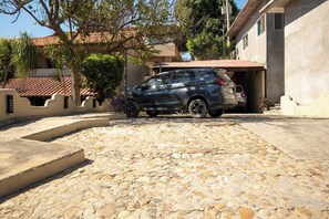 A stone-paved driveway leading to a car parked in a garage. - Tropical Hotel w/ Pool, Steps to Zicatela Beach (Puerto escondido)