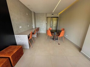 A modern conference room with a glass partition, orange chairs, and a wooden bench. - Comfort & Style in Downtown (Curitiba)