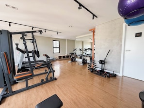 Een sportschool met diverse fitnessapparaten, waaronder loopbanden, krachtapparaten en gewichten.