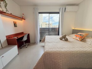 Een slaapkamer met een bed, een bureau en een raam met gordijnen.