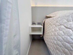 A bedroom with a bed, a nightstand, and a wall-mounted shelf. - Comfort & Style in Downtown (Curitiba)
