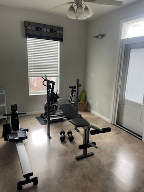 A home gym with exercise equipment, a bench, dumbbells, and a window with blinds. - Centrally Located Eugene Home w/ Patio & Air (Eugene)