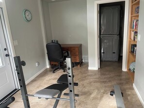 A home gym with a bench press, a squat rack, and a chair. - Centrally Located Eugene Home w/ Patio & Air (Eugene)