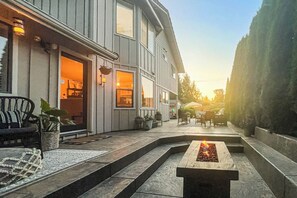 Et moderne hus med terrasse, udendørs møbler og bålsted.