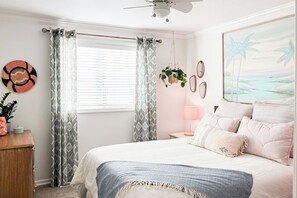 A bedroom with a bed, curtains, a wall-mounted plant, a painting, and a ceiling fan. - Happy Heart House | Hot Tub | Firepit (Eugene)