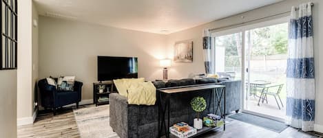 A modern living room with a sofa, TV, and a dining area with chairs.