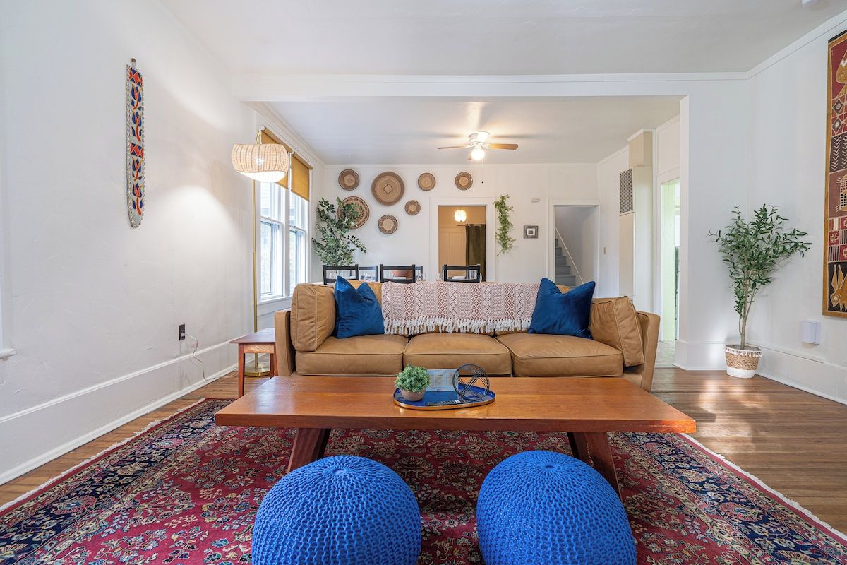 A living room with a brown sofa, blue cushions, a wooden coffee table, and a patterned rug.