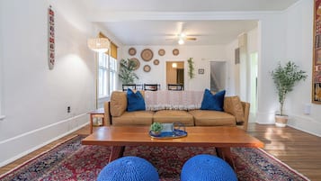 A living room with a brown sofa, blue cushions, a wooden coffee table, and a patterned rug.