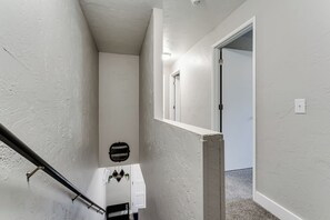 A narrow stairway with a handrail, white walls, and a door at the top. - PNW Forest Getaway w/Fenced Yard & Central Air (Eugene)