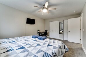 A bedroom with a bed, a ceiling fan, a desk with a chair, and a television. - PNW Forest Getaway w/Fenced Yard & Central Air (Eugene)