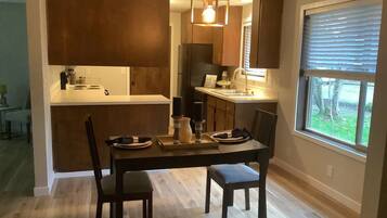 Une cuisine moderne avec des meubles de couleur sombre, un îlot central et un coin repas comprenant une table et des chaises.