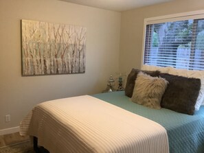 A bedroom with a bed, pillows, a wall-mounted artwork, a window with blinds, and a nightstand with a lamp. - 2 Bedroom desirable Ferry Street Bridge ! Casa 15 (Eugene)