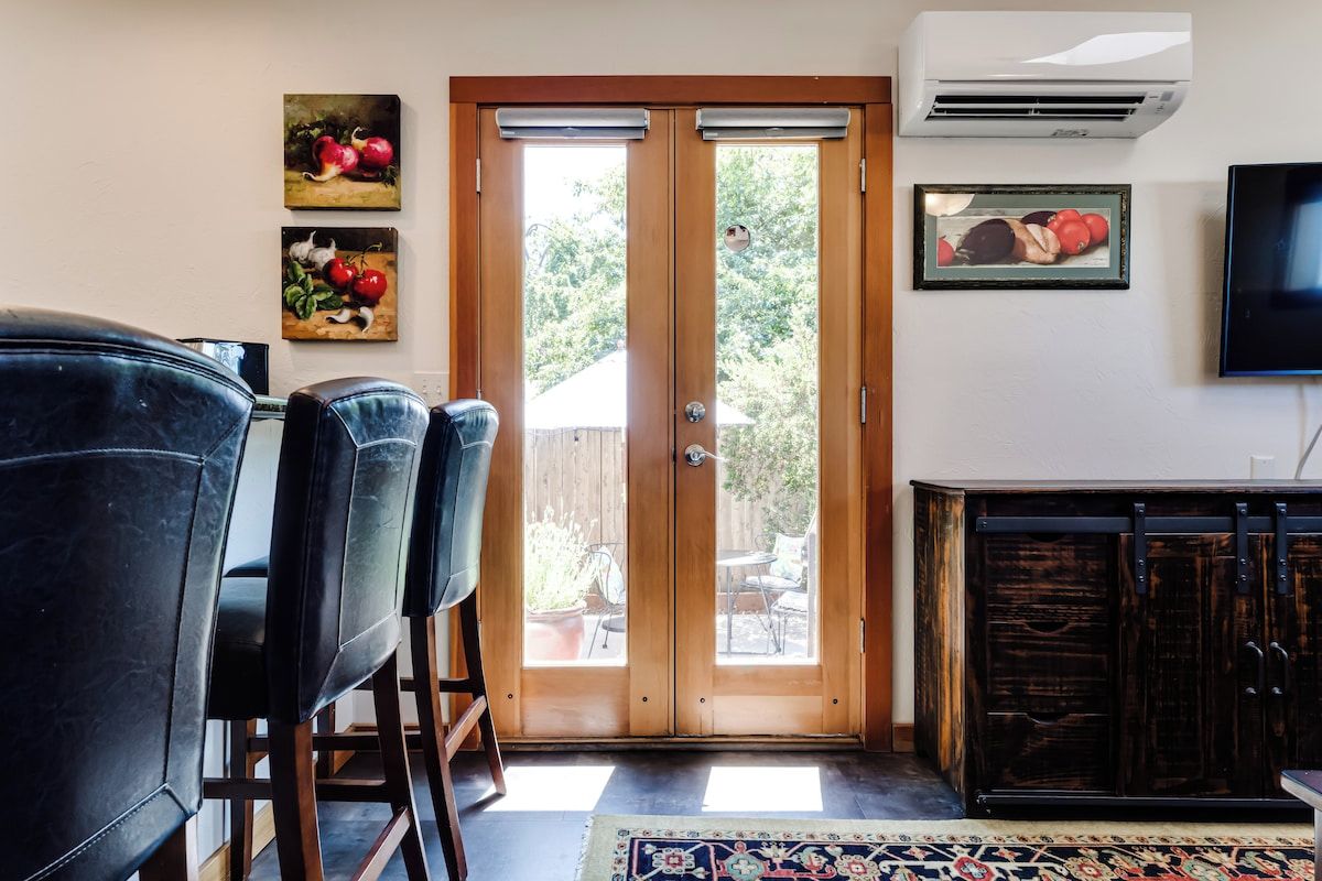 A dining area with a wooden door leading to a patio, a television mounted on the wall, and a cabinet with a rustic finish.