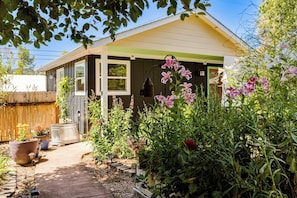 A residential property with a covered porch, a pathway leading to the house, and various potted plants and flowers. - Amazon Area Backyard ADU With Private Entrance (Eugene)