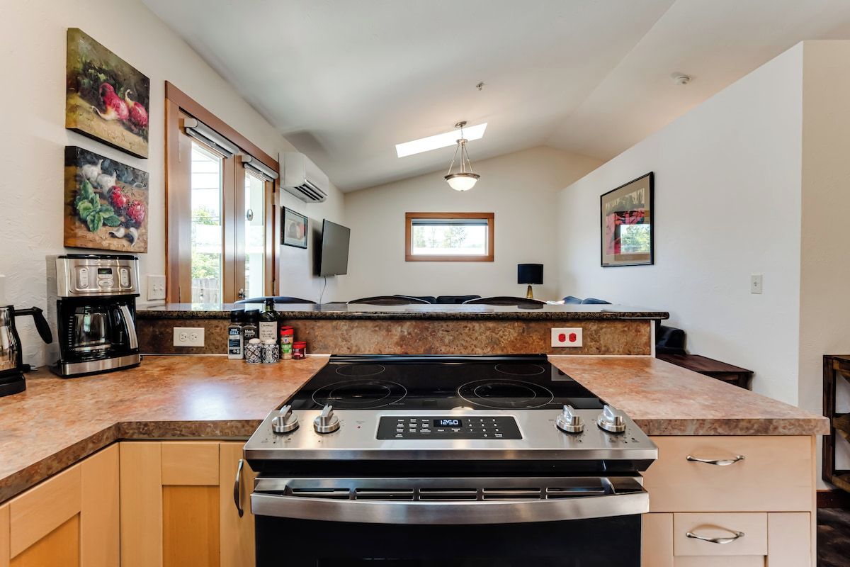 Una cocina con estufa integrada, cafetera y ventana.