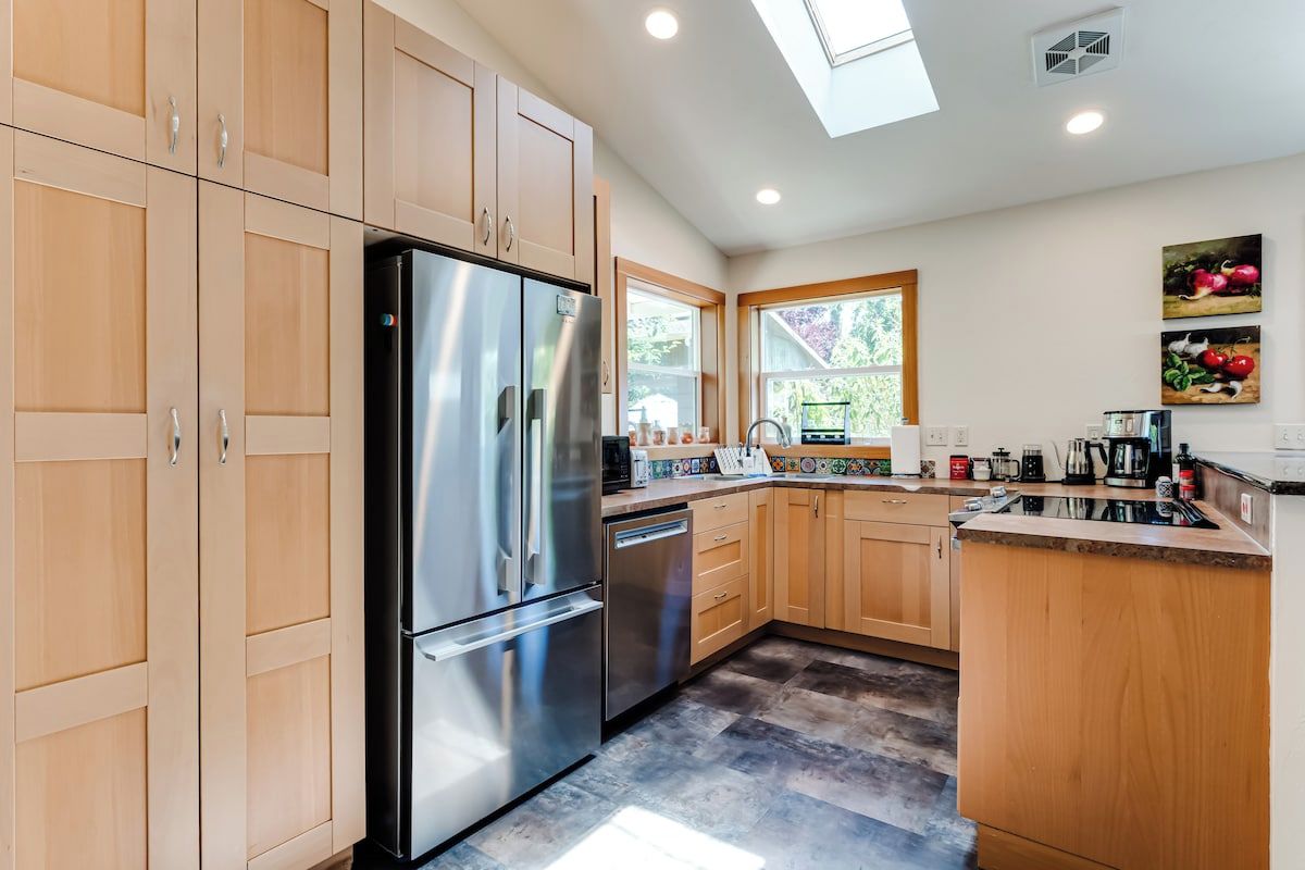 A modern kitchen with wooden cabinets, stainless steel appliances, and a window providing natural light.