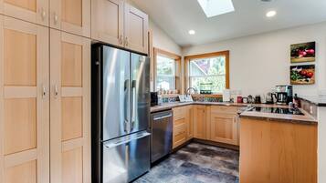 A modern kitchen with wooden cabinets, stainless steel appliances, and a window providing natural light.