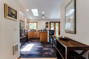 A modern kitchen with a central island, wooden cabinets, and a dining area with a wooden table.