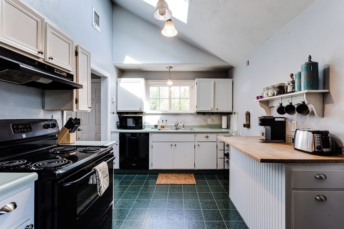 A kitchen with a stove, microwave, sink, and cabinets.