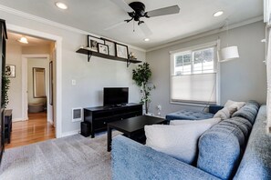 A living room with a sofa, a television, and a ceiling fan. - Pet-Friendly House w/ Backyard & Free Parking (Springfield)
